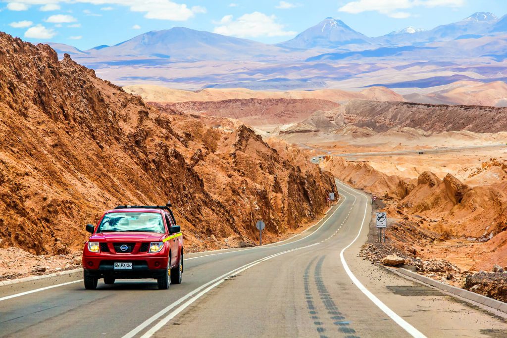 A picture of a red Nissan Navara driving through a desert in Chile.