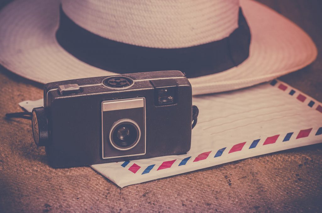A picture of a retro camera and tourist hat.