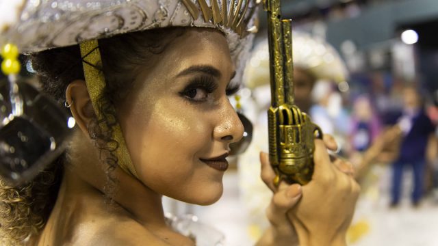 A picture of a female dancer with a toy gun at the rio carnival.